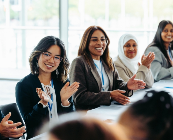 Diverse group of people at a meeting looking happy and applauding